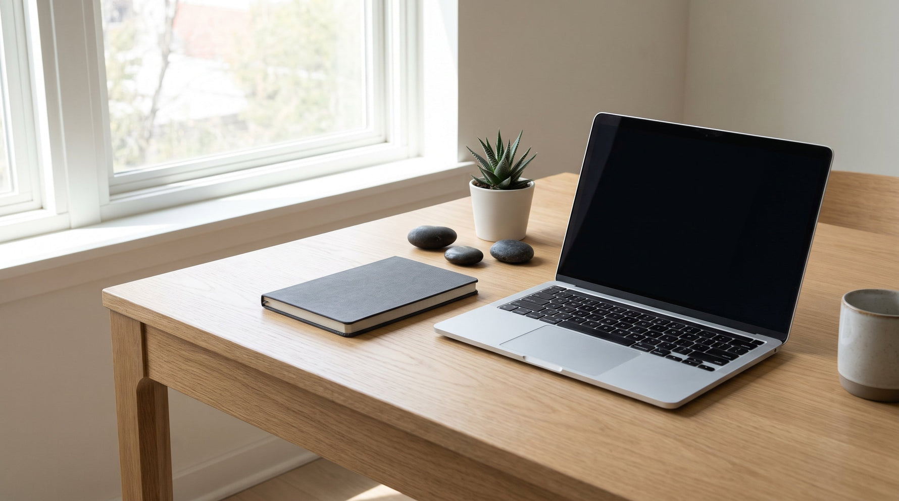 Minimal çalışma masasında laptop ve üç taş